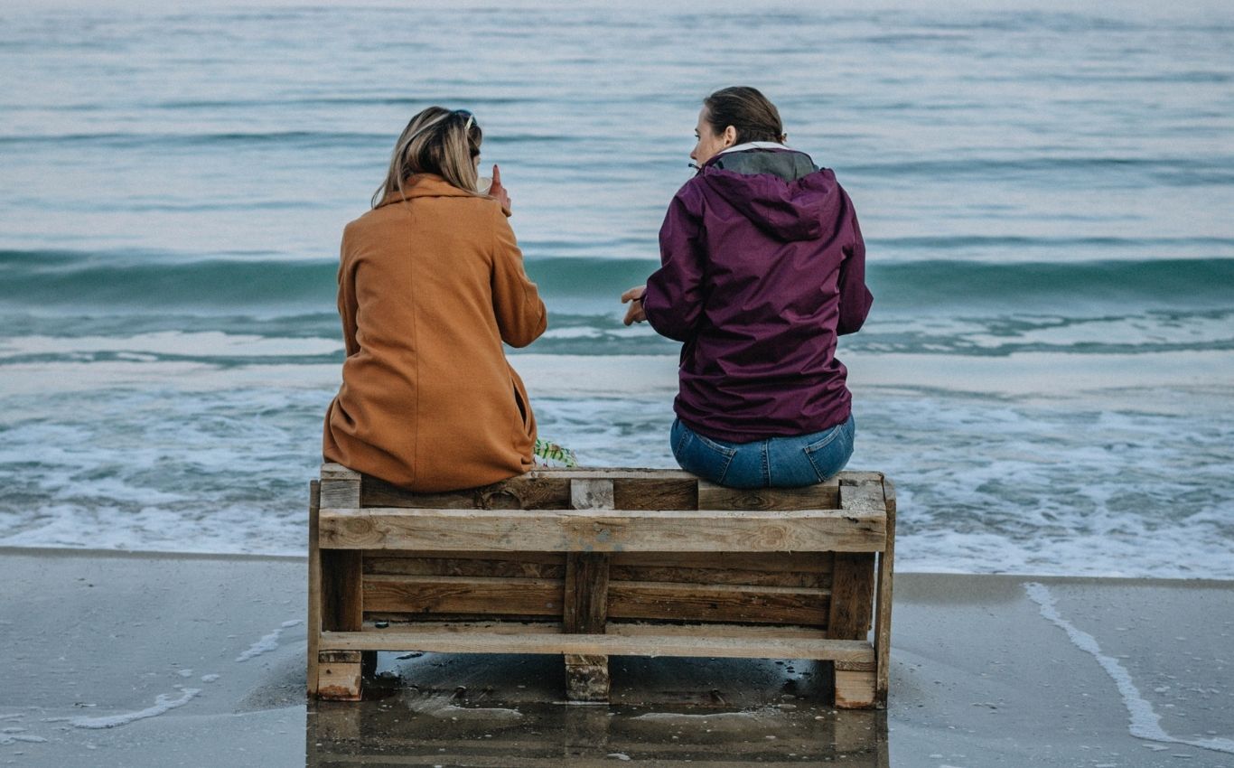 Zwei Frauen sitzen nebeneinander an der Nordsee