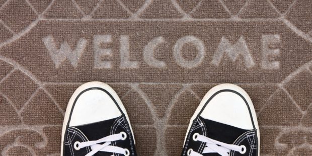 Zwei Füße auf einer Fußmatte auf der "Welcome" steht