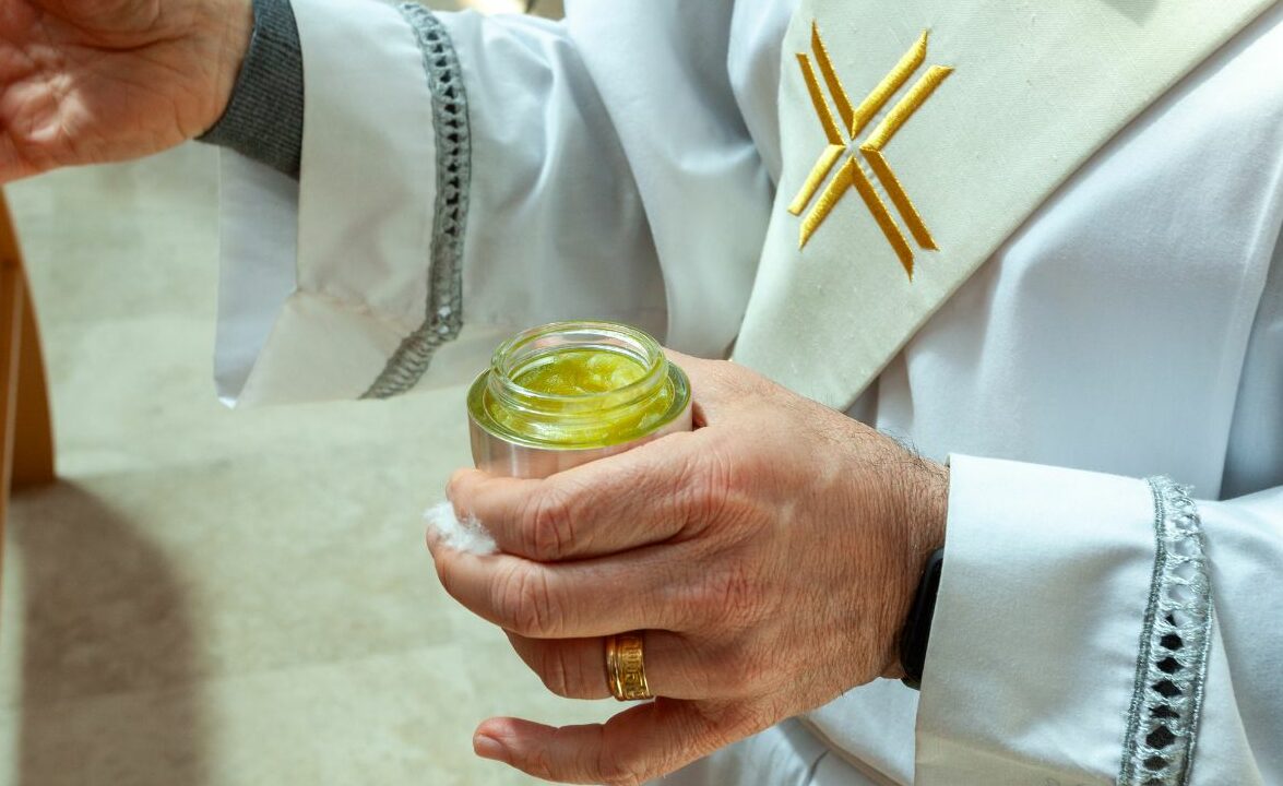Priester mit einer Dose Chrisamöl