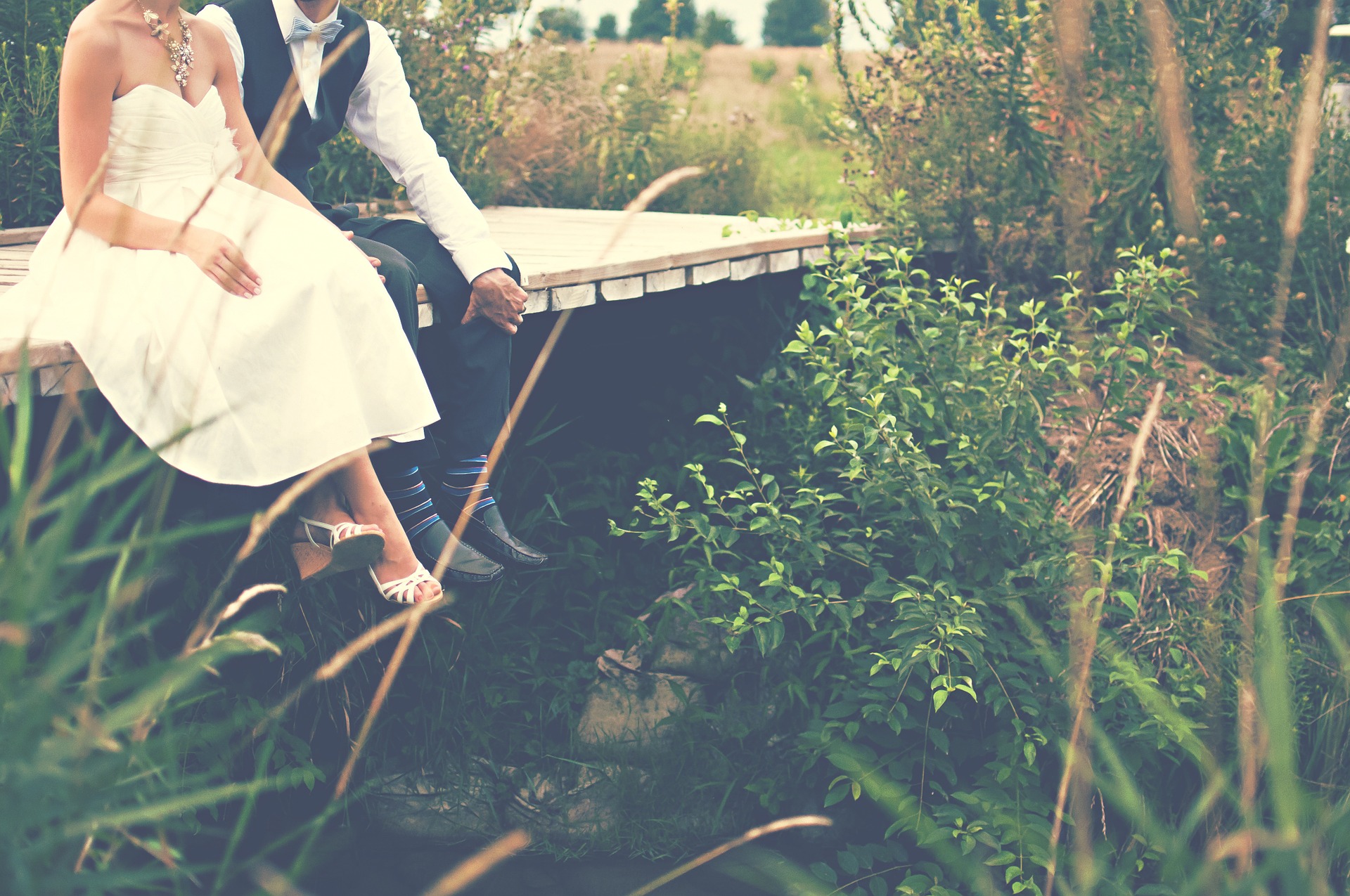 Hochzeitspaar sitzt auf einer Brücke