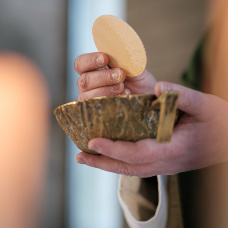Hände, die Brot über einer Schale halten