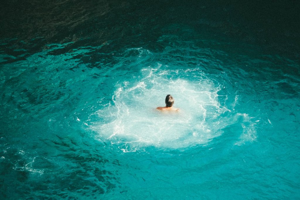 Mensch schwimmt allein im Wasser mit Strudeln