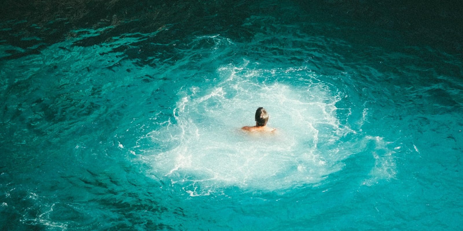 Mensch schwimmt allein im Wasser mit Strudeln