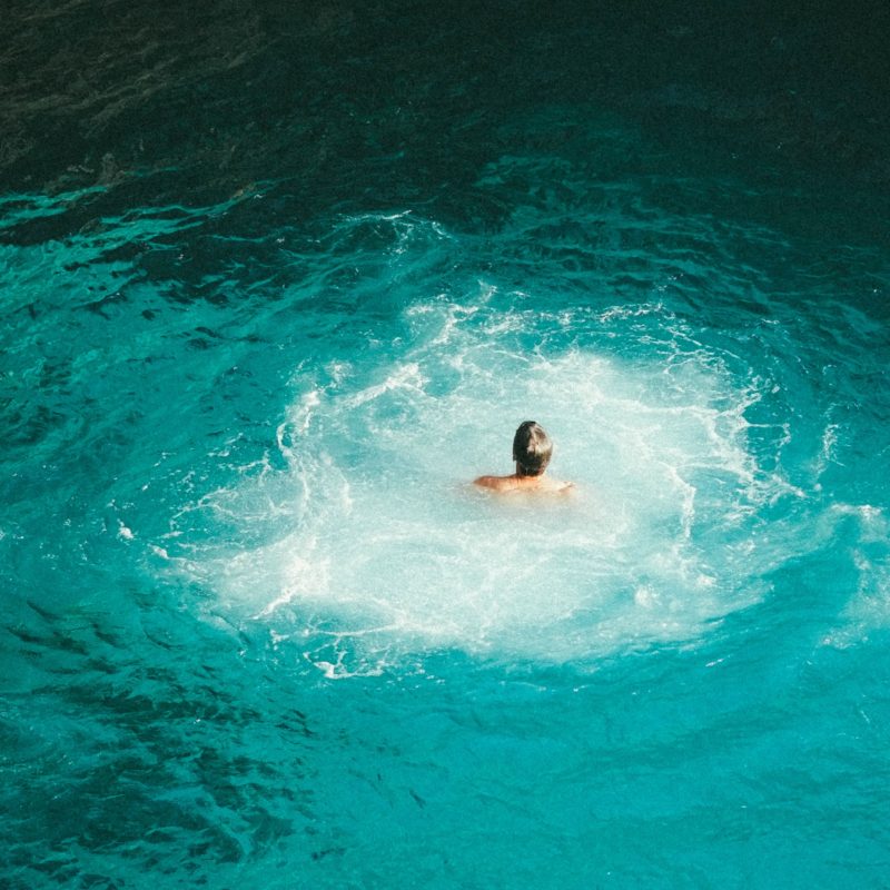 Mensch schwimmt allein im Wasser mit Strudeln