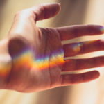 Hand, auf der sich Regenbogenfarben befinden