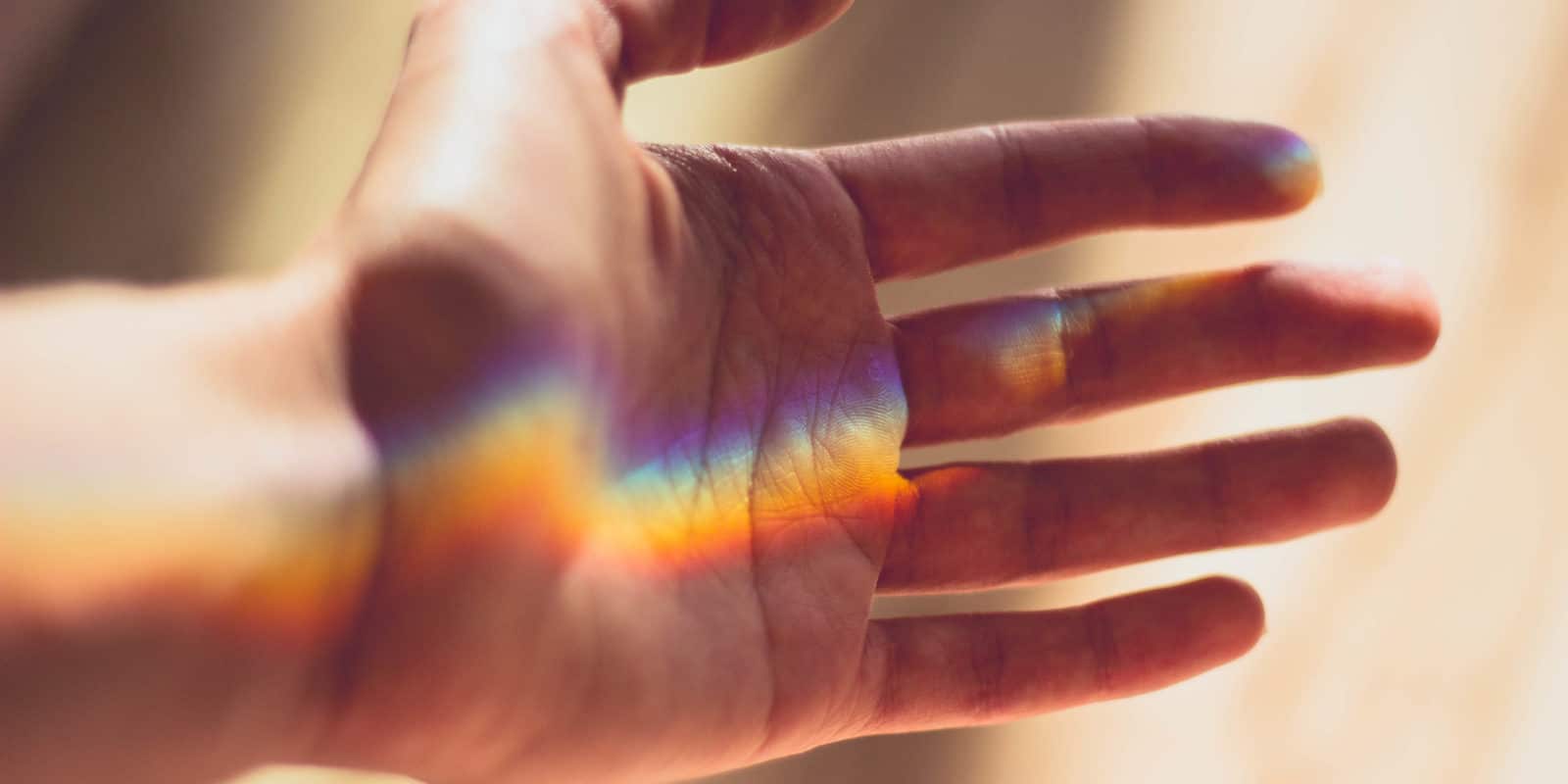 Hand, auf der sich Regenbogenfarben befinden