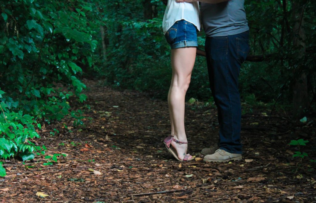 Mann und Frau stehen sich gegenüber auf einem Waldweg, nur Unterköroper zu sehen