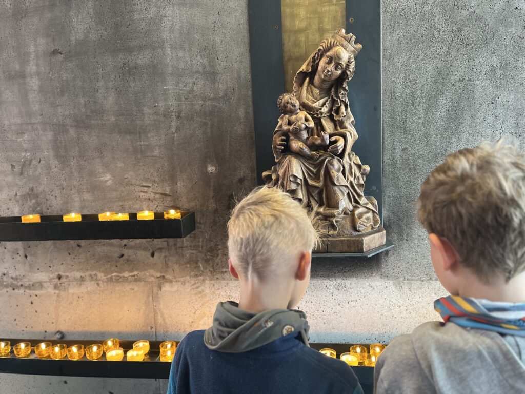 Kinder zünden in der Kirche eine Kerze an