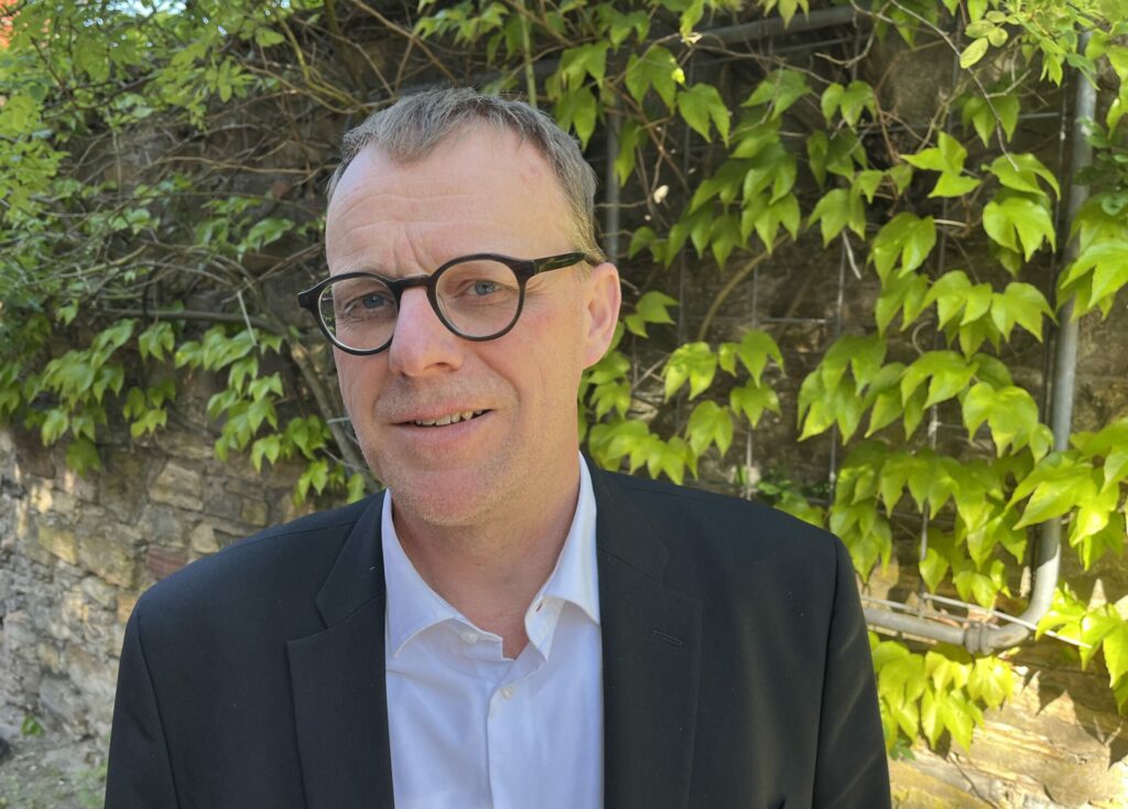 Porträt von Klaus gr. Beilage vor einer bewachsenen Mauer