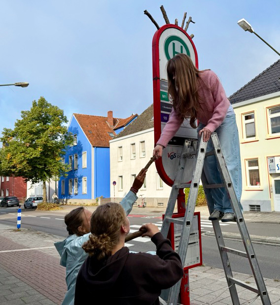 Schülerinnen befestigen Holz an einer Bushaltestelle