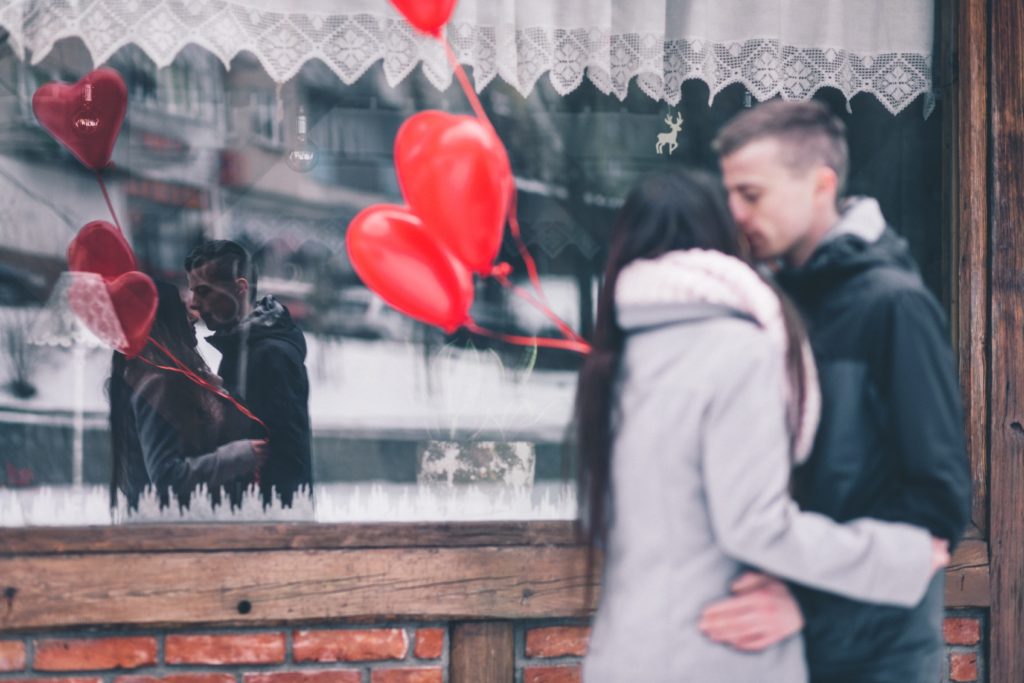 junges Paar mit roten Herzluftballons