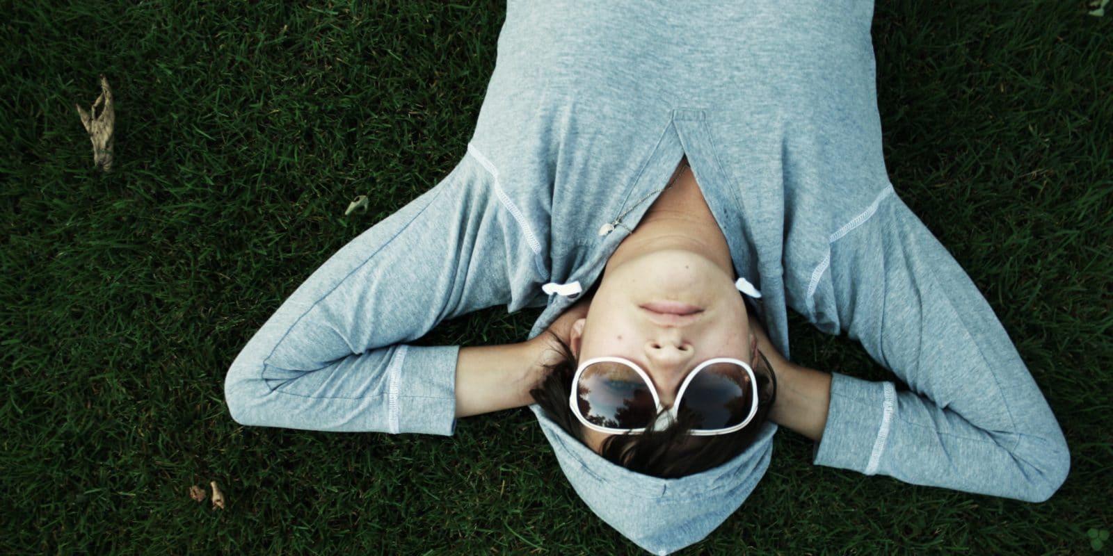 Mann mit Sonnenbrille liegt auf Wiese