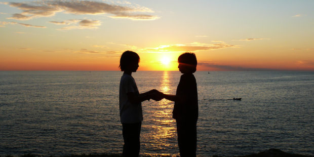 Zwei Kinder halten am Strand Händchen