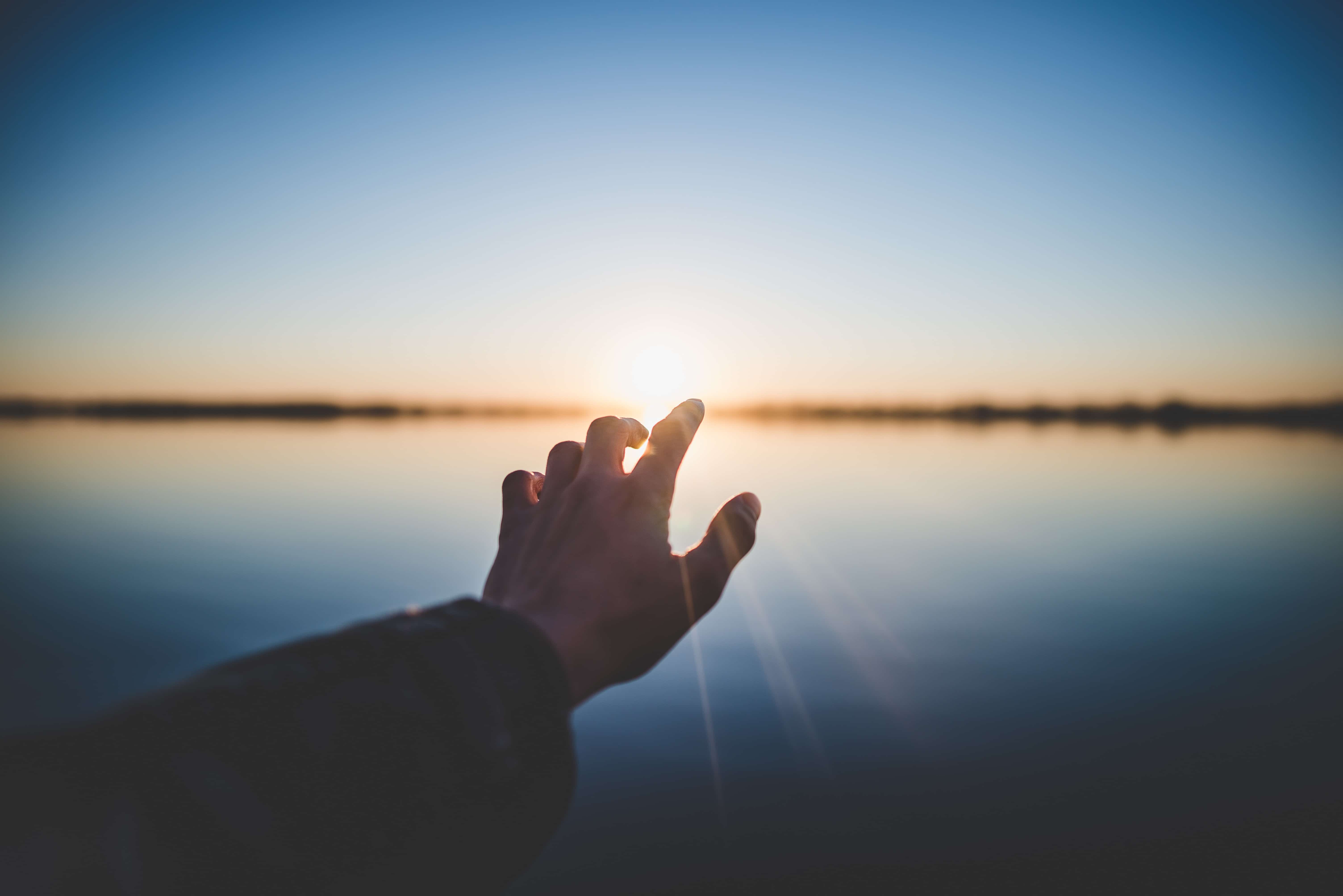 Eine Hand wird zum Licht ausgestreckt