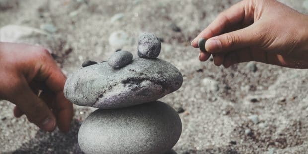 Hände bauen Trum aus Steinen