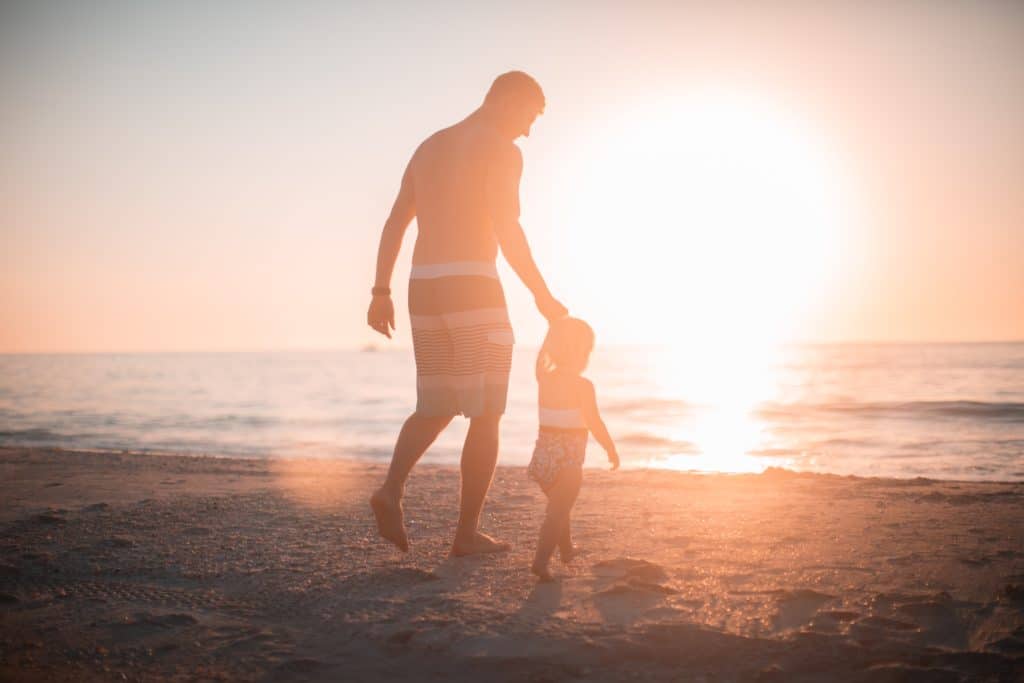 Vater mit Kind am Strand vor Sonnenuntergang