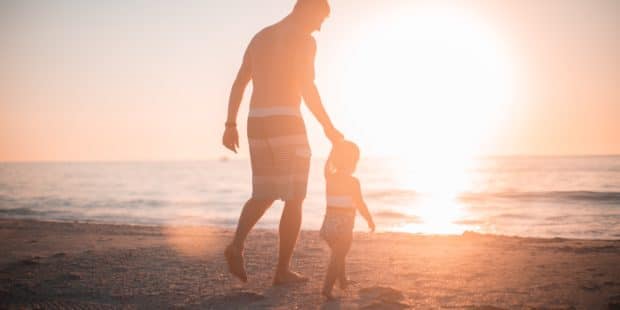 Vater mit Kind am Strand vor Sonnenuntergang