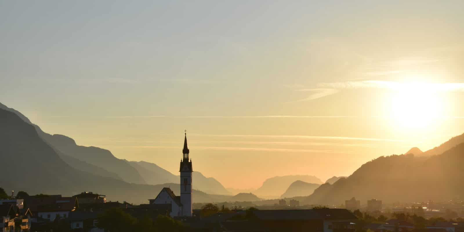 Dorf mit Bergen und Sonnenaufgang