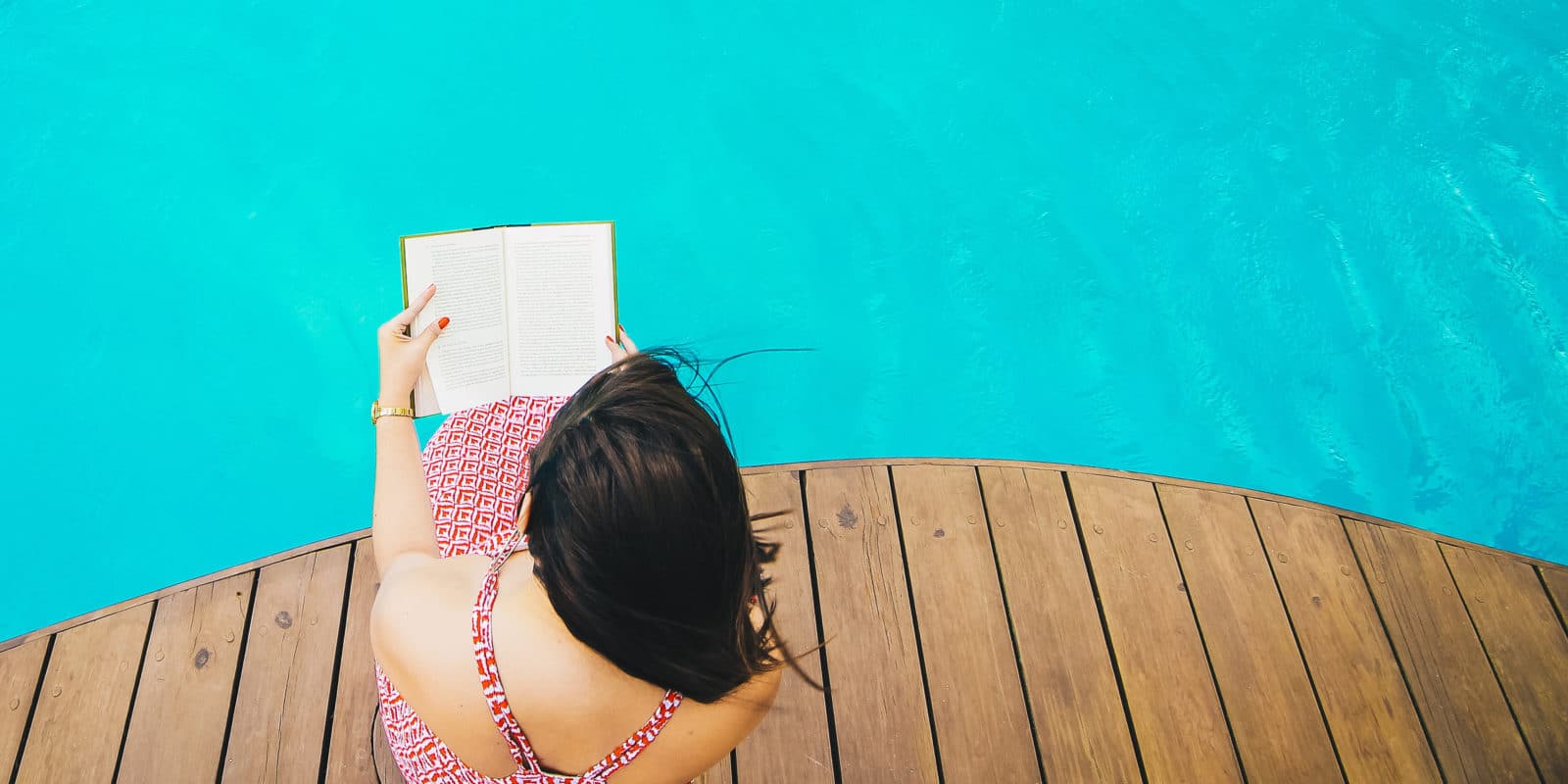 Frau liest am Swimmingpool