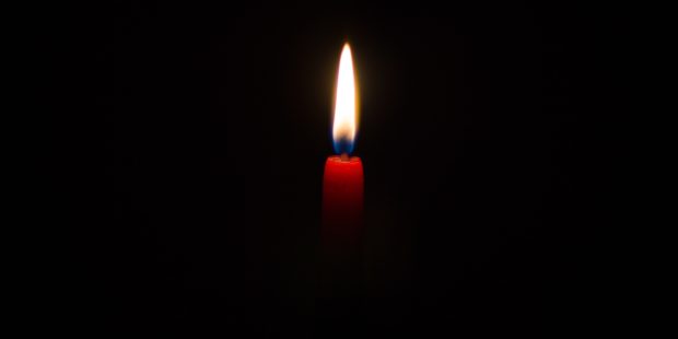 eine rote Kerze brennt in der Dunkelheit