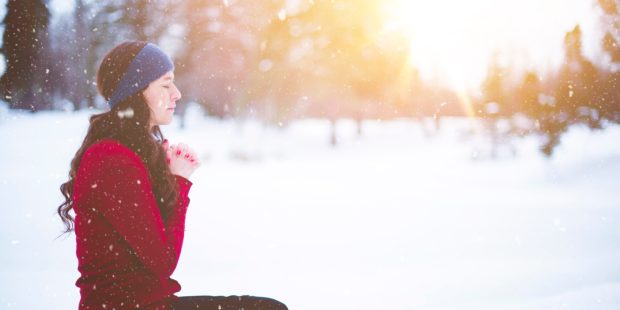 Frau sitzt im Schnee und betet