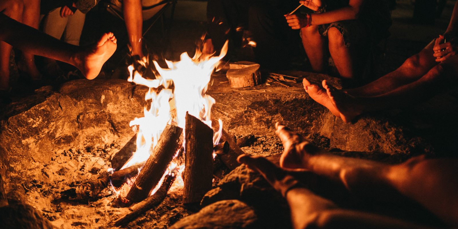 Menschen sitzen um ein Lagerfeuer