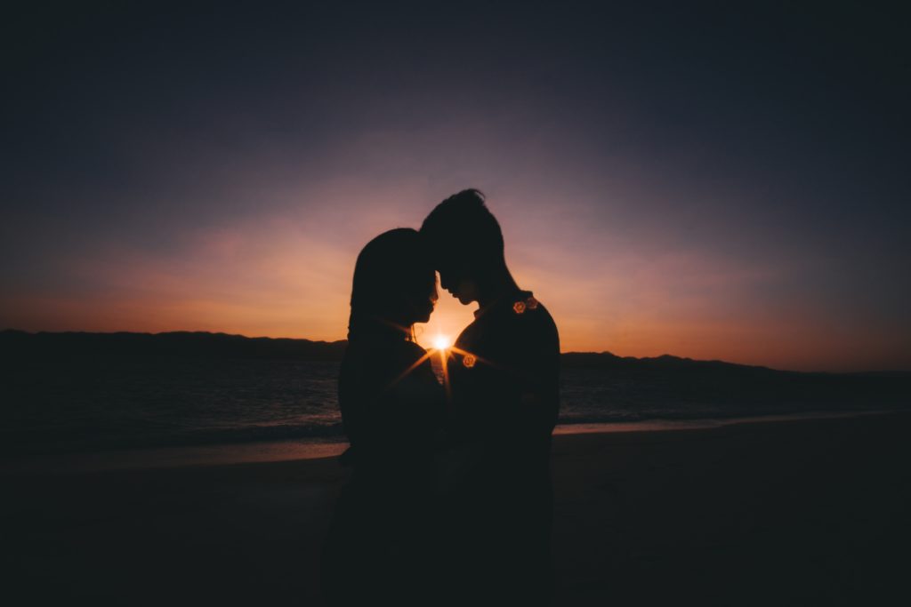 Mann und Frau küssen sich vor Sonnenuntergang