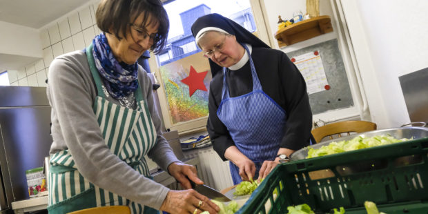 Schwester Benedicta udn eine Ehrenamtliche bereiten in der Küche der Wärmestube Essen zu.
