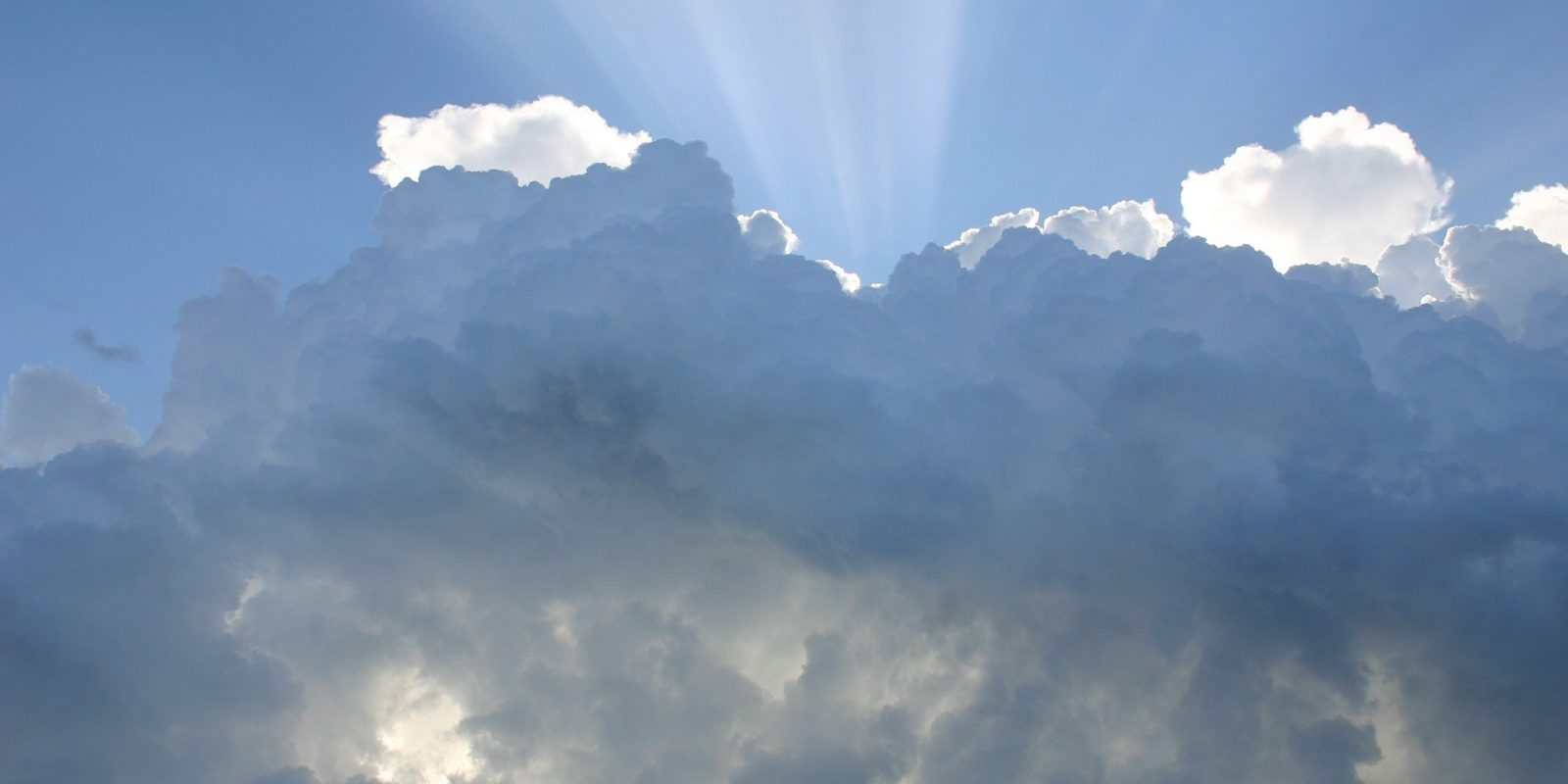 Ein blauer Himmel mit Wolken und Sonnenstrahlen