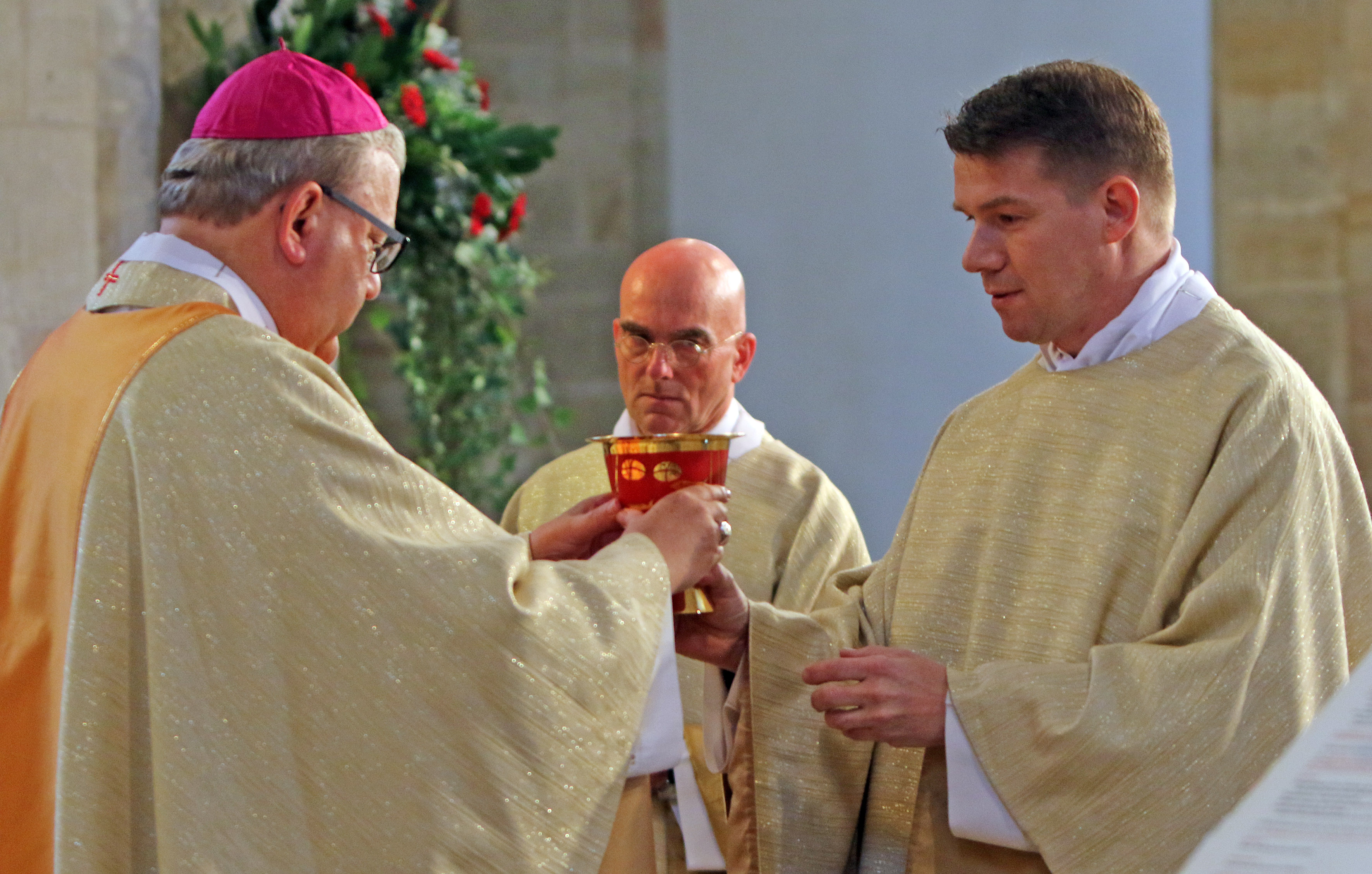 Bischof und zwei Neupriester mit dem Kelch