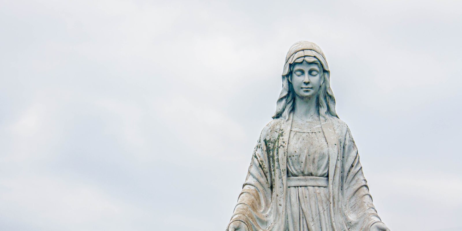 Eine Marienstatue vor bewölktem Himmel