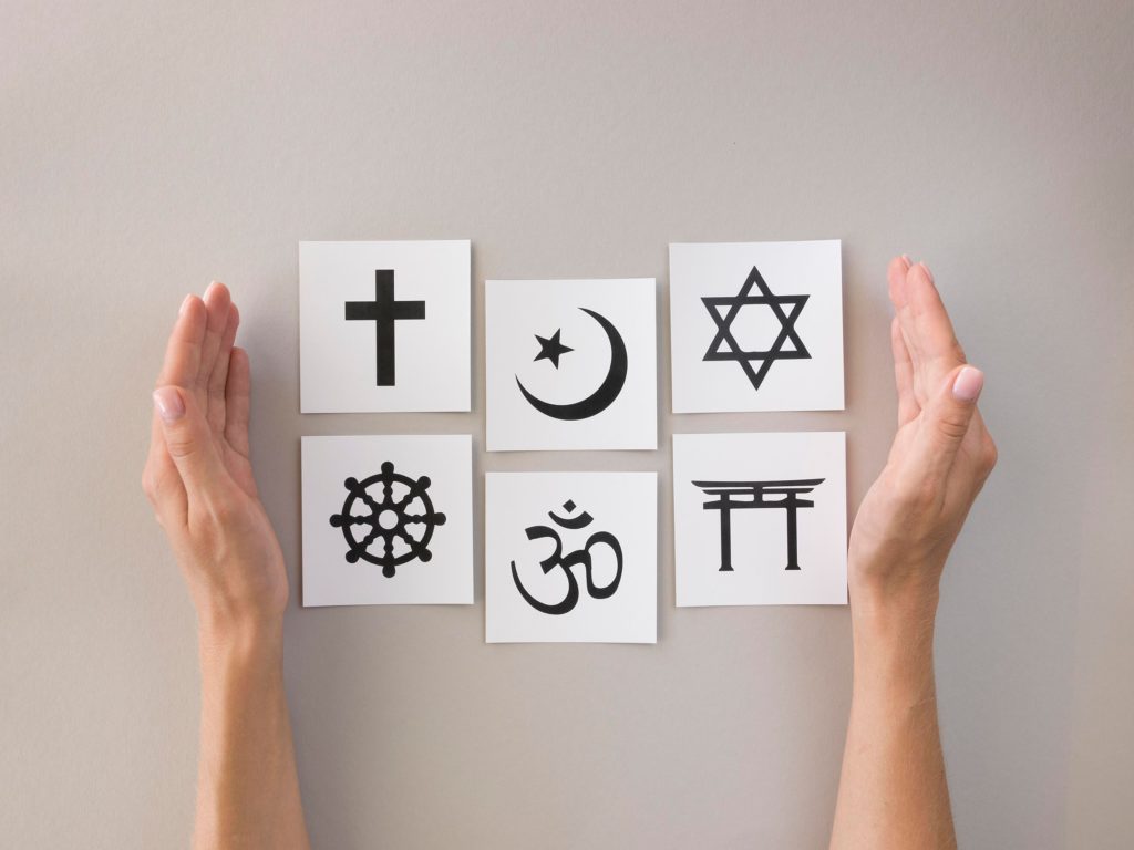 Hand umschließt Symbole der Weltreligionen