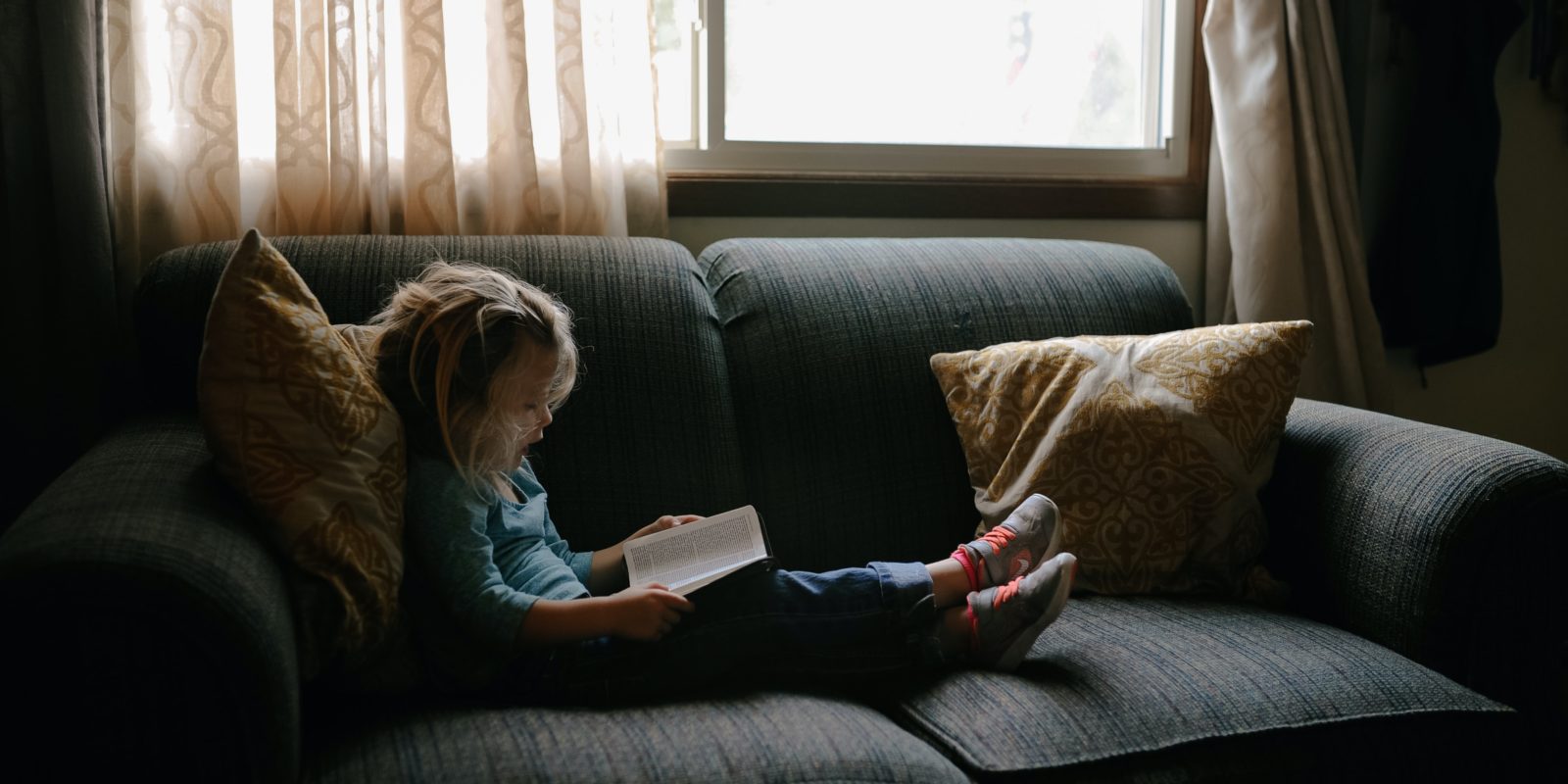 Kind auf dem Sofa liest ein Buch