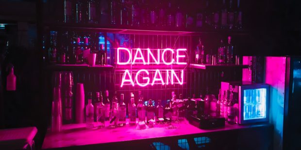 LED-Schrift "Dance Again" an einer Theke
