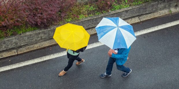 zwei Menschen mit Regenschirmen