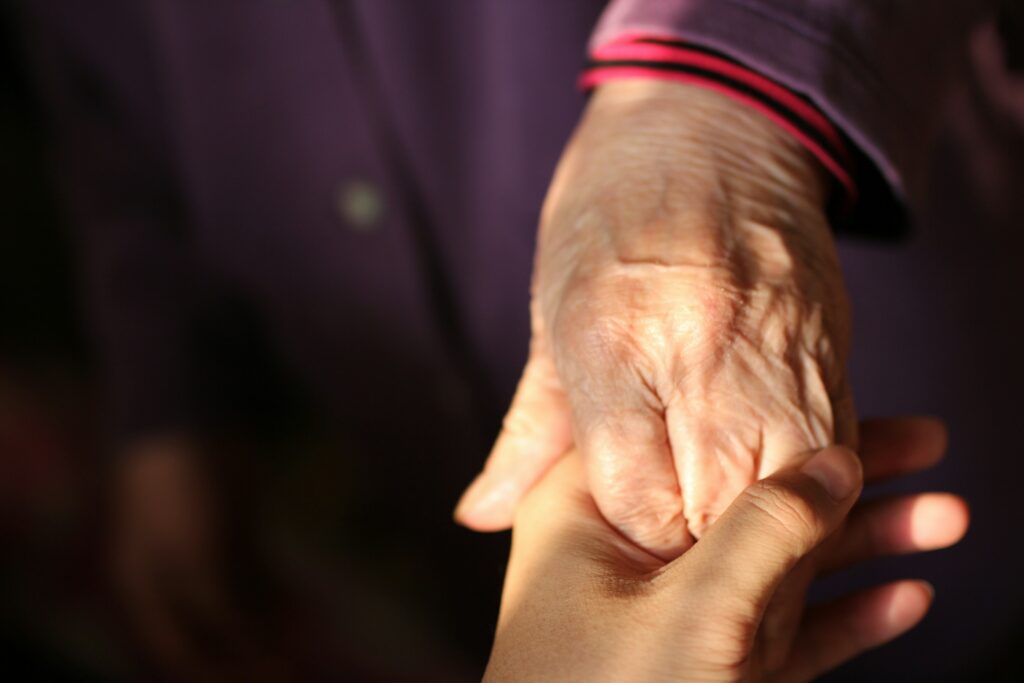 Person hält Hand eines älteren Menschen