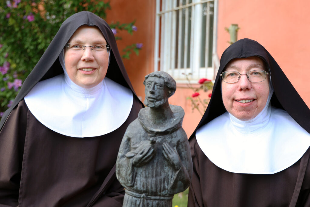 Schwester Fidelis (rechts) und Schwester Gratia im Garten von Kloster Lage. Im Vordergrund eine Statue des heiligen Franziskus von Assisi.