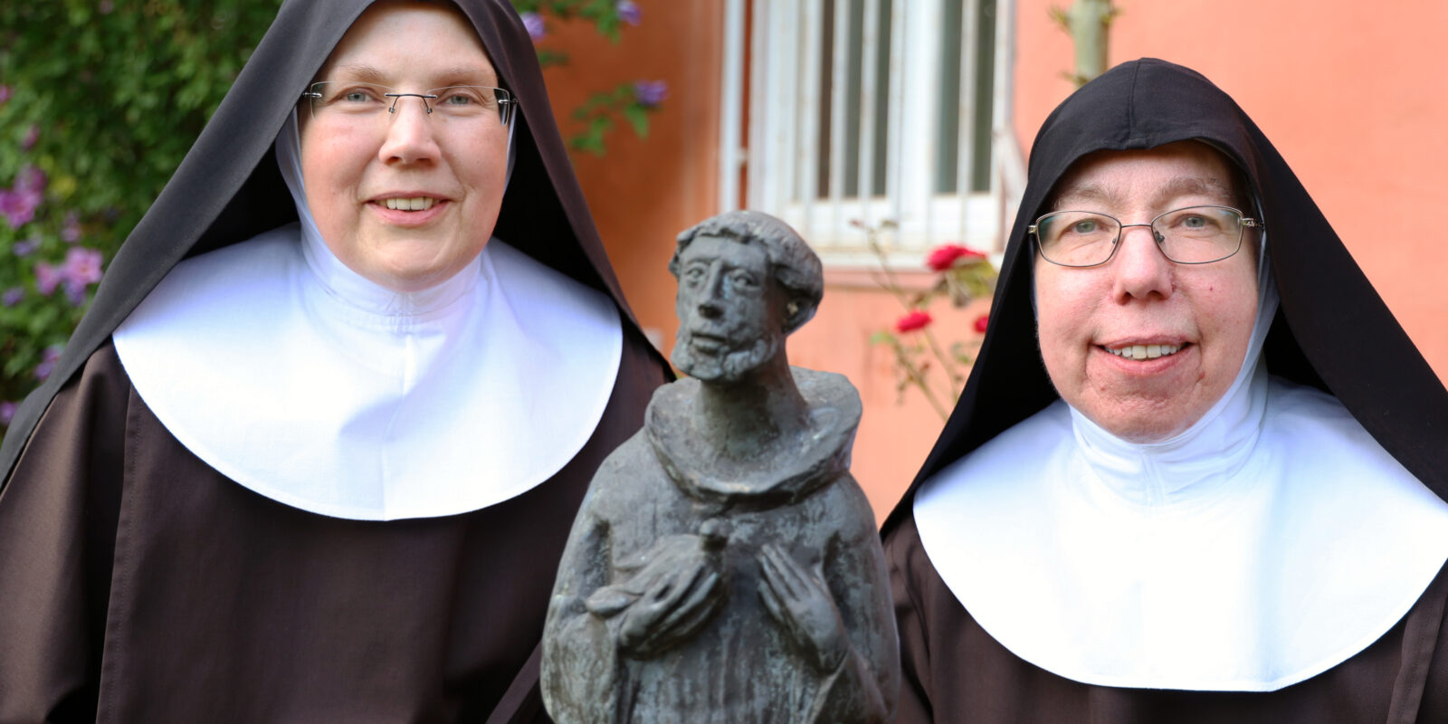 Schwester Fidelis (rechts) und Schwester Gratia im Garten von Kloster Lage. Im Vordergrund eine Statue des heiligen Franziskus von Assisi.