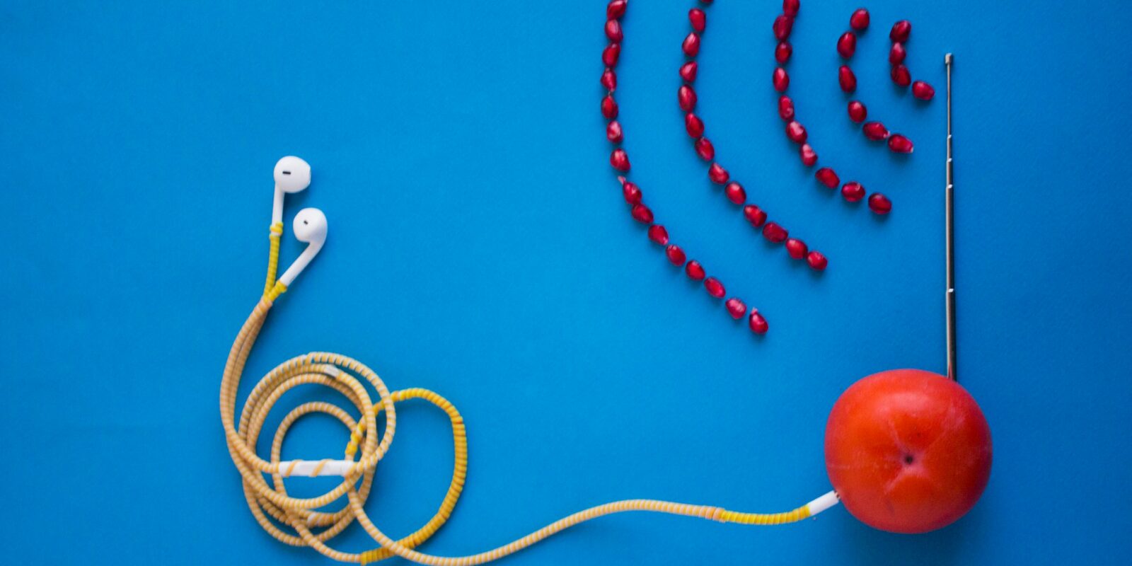 white earbuds connected to orange tomato with antenna
