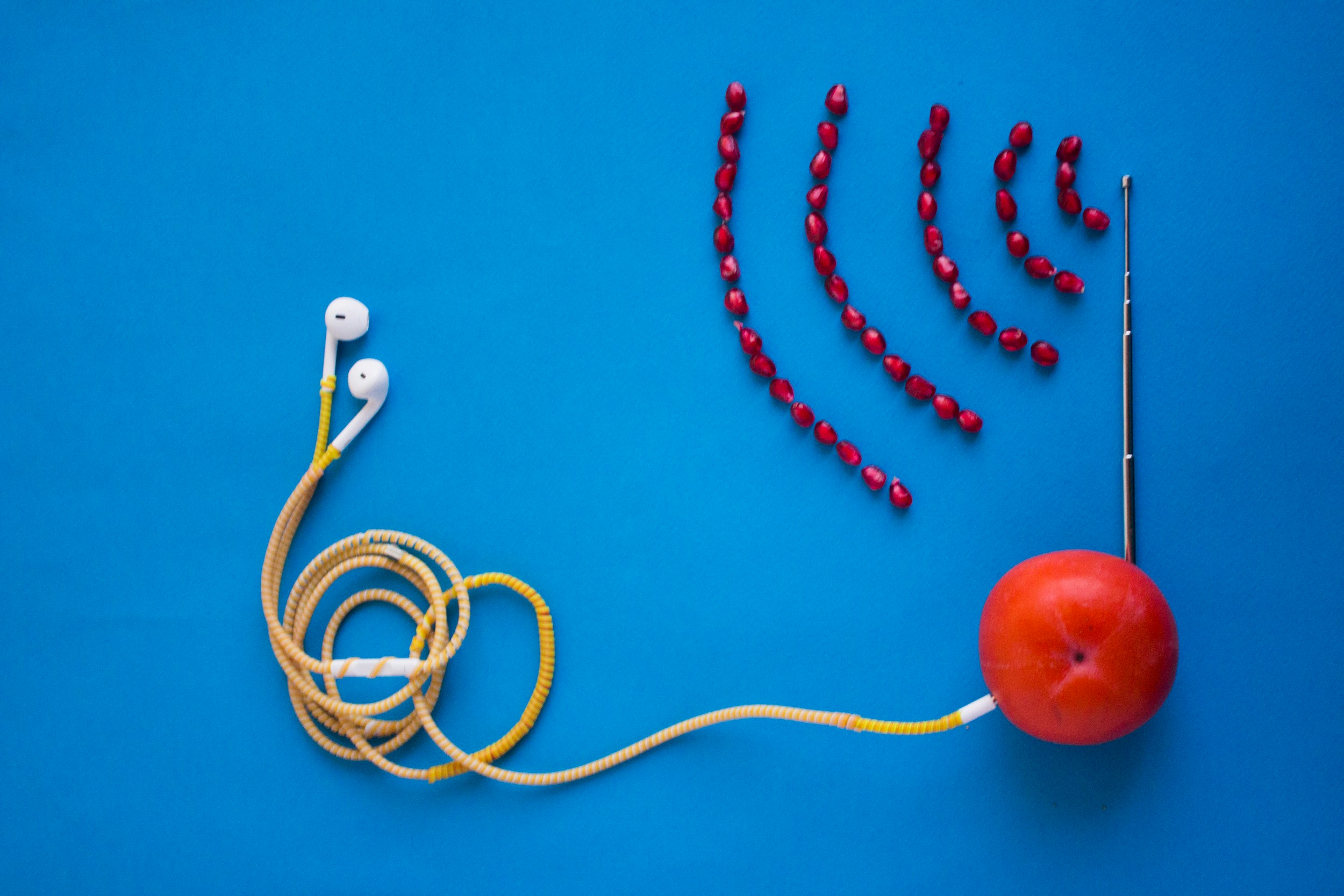 white earbuds connected to orange tomato with antenna