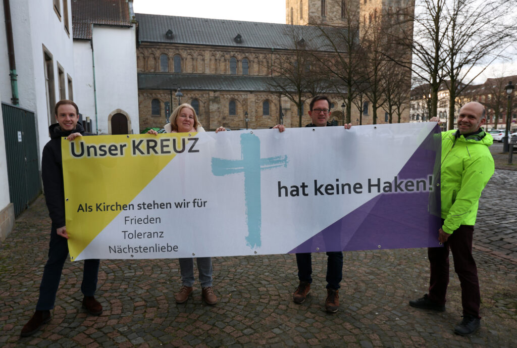 „Unser Kreuz hat keine Haken“ – das Banner der Aktion wird ab dem 27. Januar an Kirchen und kirchlichen Gebäuden in Osnabrück und der umliegenden Region hängen. Auf dem Foto (von links) Cedrik Fritz, Marita Moro, Frank Hemme-Pelzer von der katholischen Domgemeinde St. Petrus in Osnabrück und Friedemann Keller von der evangelischen Kirchengemeinde St. Michaelis.