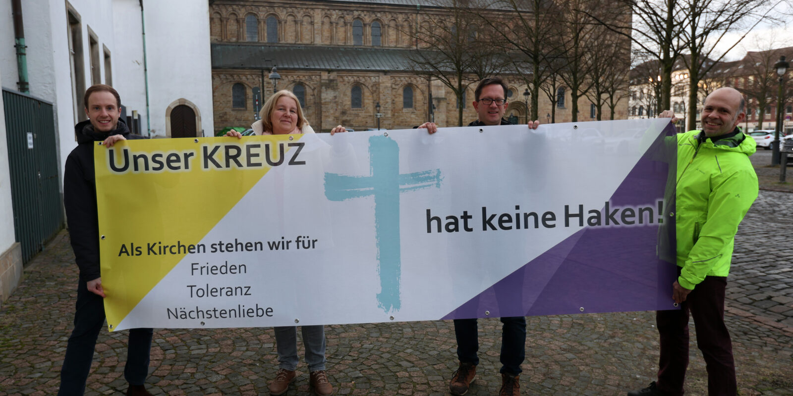 „Unser Kreuz hat keine Haken“ – das Banner der Aktion wird ab dem 27. Januar an Kirchen und kirchlichen Gebäuden in Osnabrück und der umliegenden Region hängen. Auf dem Foto (von links) Cedrik Fritz, Marita Moro, Frank Hemme-Pelzer von der katholischen Domgemeinde St. Petrus in Osnabrück und Friedemann Keller von der evangelischen Kirchengemeinde St. Michaelis.