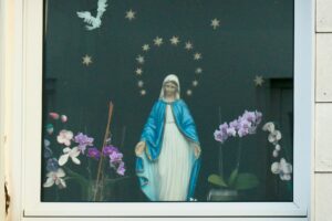 Maria auf dem Fensterbrett neben Orchideen