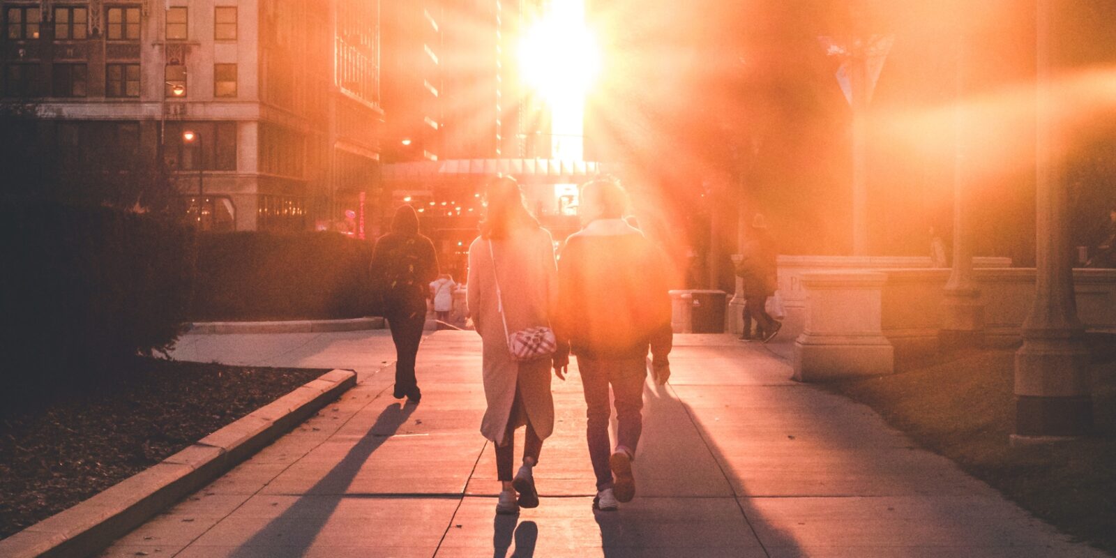 Zwei Menschen laufen zusammen zwischen Häusern Richtung Sonnenuntergang