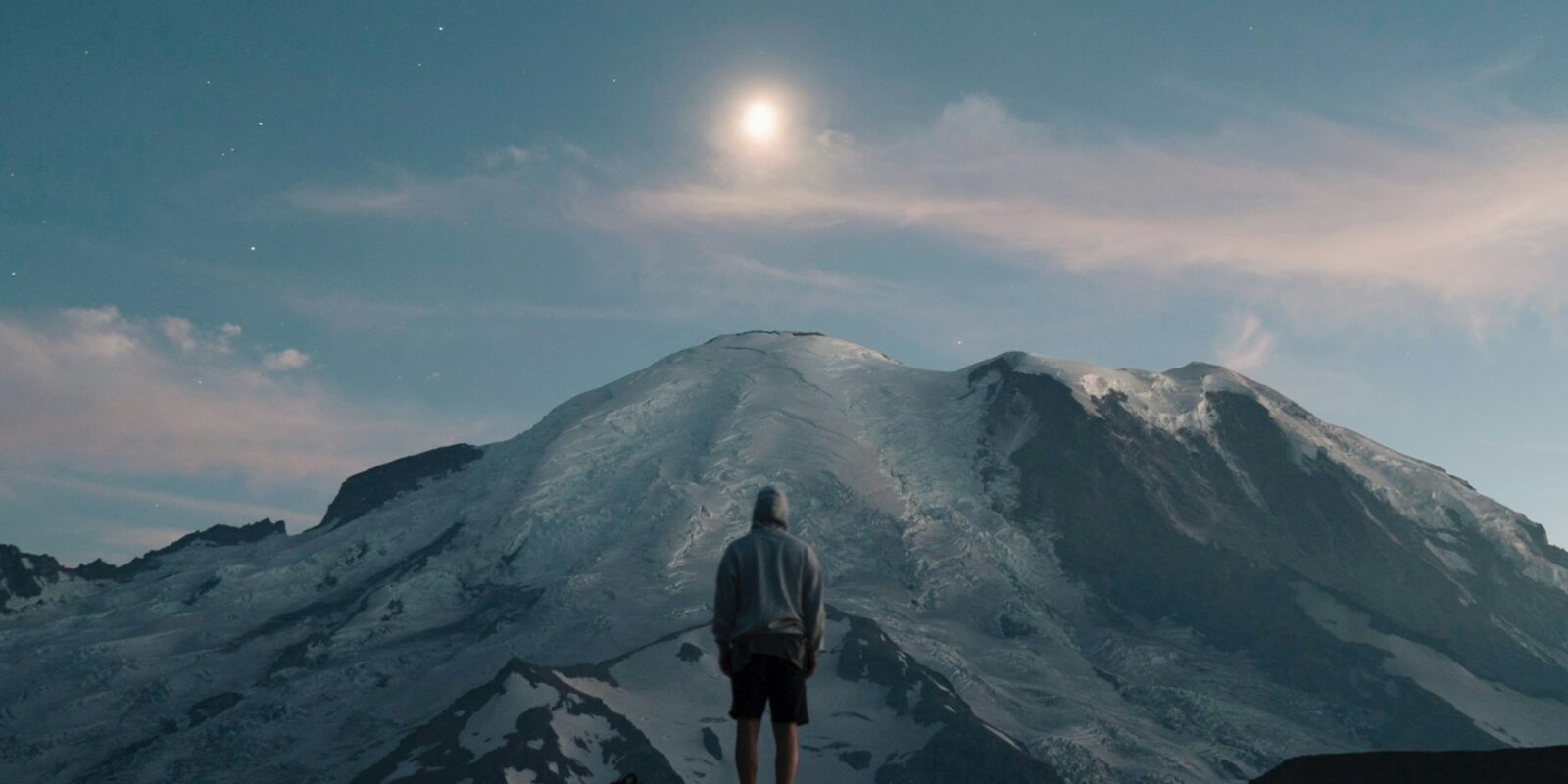 man standing on grass field overlooking mountain