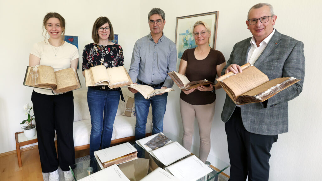Präsentieren die restaurierten Bände aus dem Pfarrarchiv St. Johann: (von links) Lena Witteborg (Auszubildende im Bistumsarchiv), Janine Wasmuth (Praktikantin), Georg Wilhelm (Archivar), Dagmar Dornheim (Restauratorin) und Martin Schomaker (Dechant und Pfarrer von St. Johann).