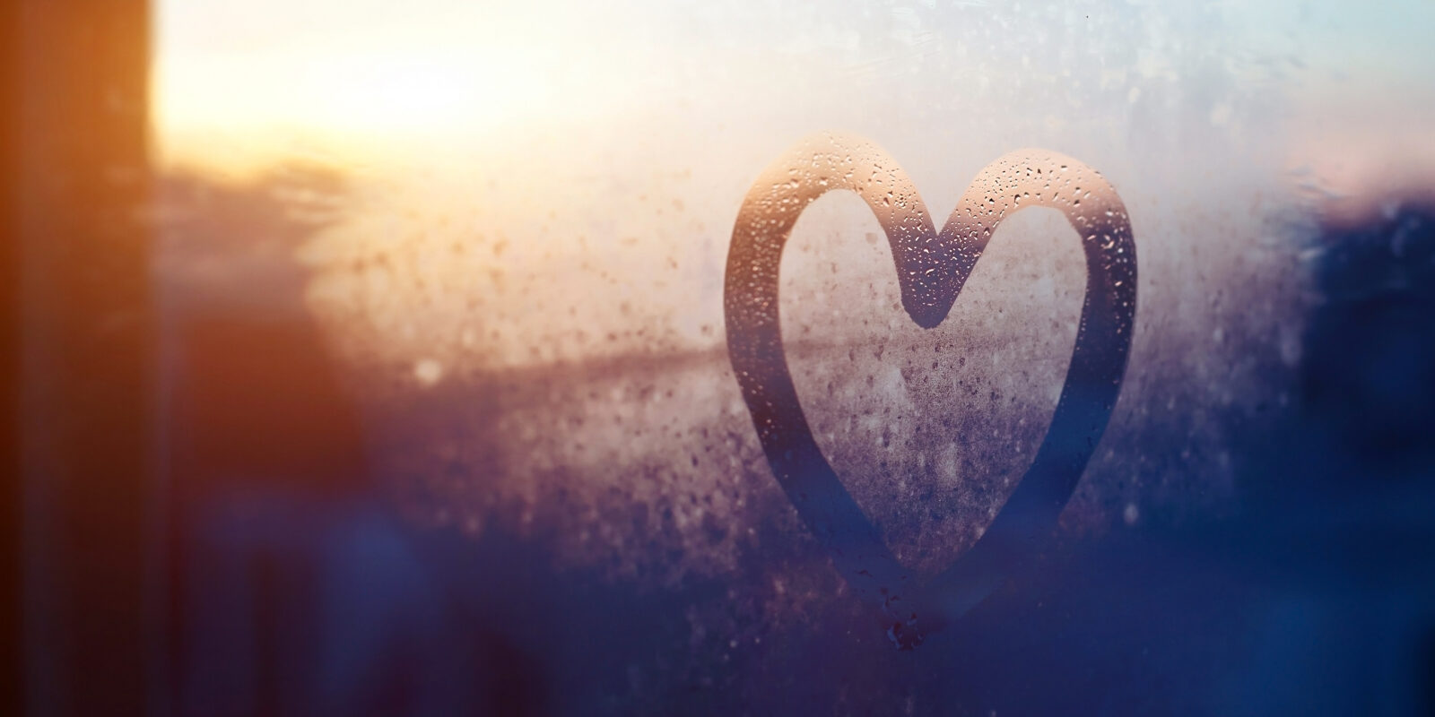 Herz an beschlagener Scheibe im Sonnenaufgang