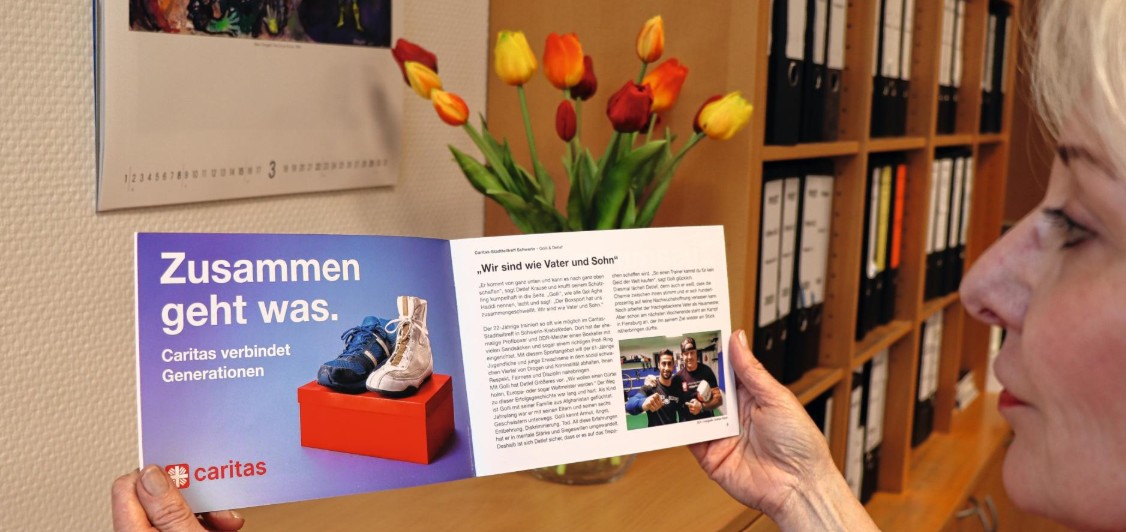 Eine Frau mit aufgeschlagener Caritas-Broschüre