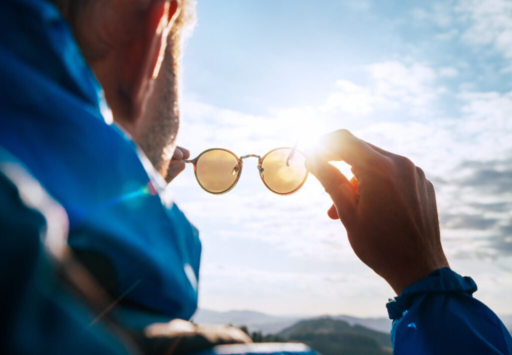 Mann hält Sonnenbrille in die Sonne