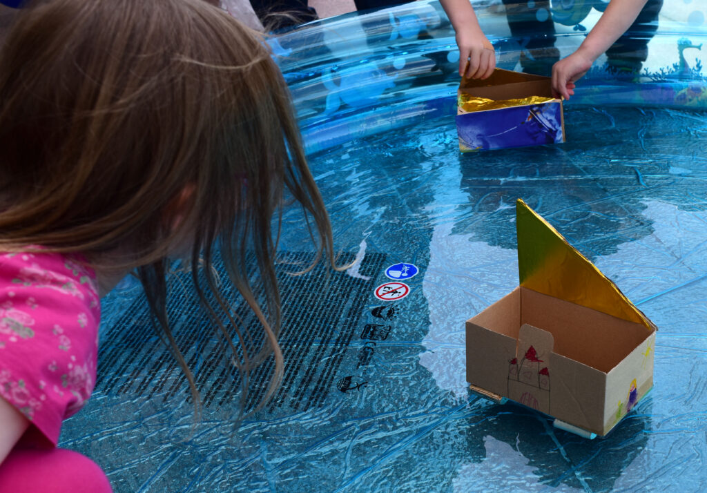 Kinder spielen mit selbstgebauten Booten auf dem Wasser